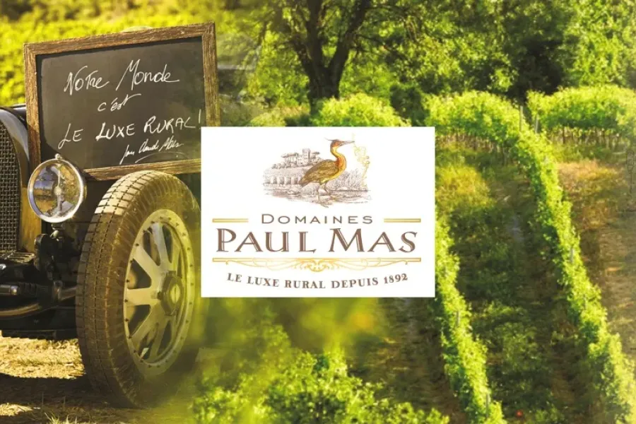 Man sitting next to a car with the paul mas logo next to him