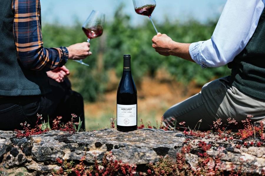 A bottle of wine and cups in a toast