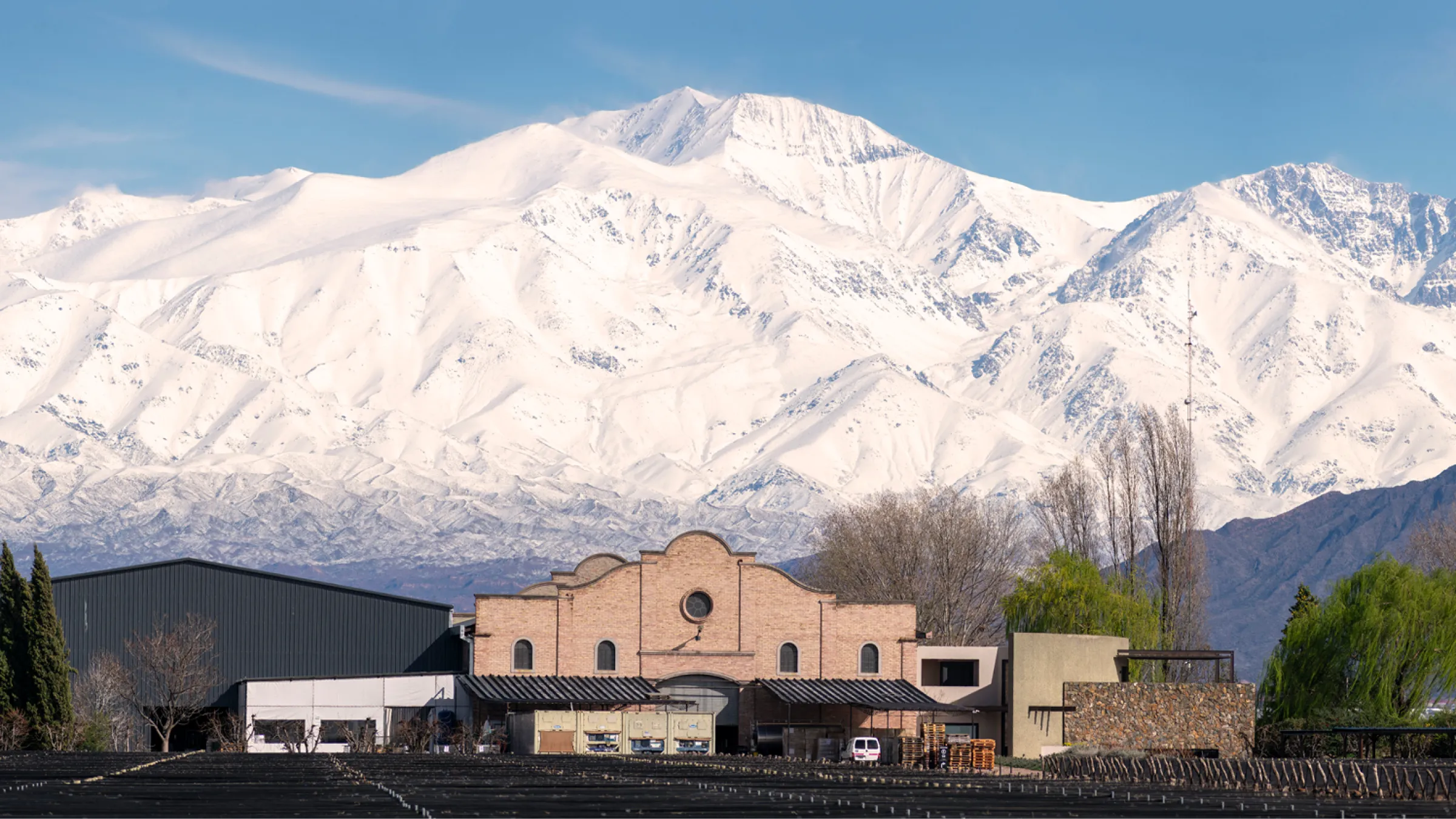 Close view of the Las Perdices bodega with mountains in the back covered in snow